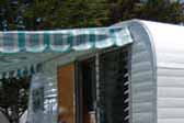 Picture of bright turquoise, blue and white striped awning on a 1957 Field and Stream vintage trailer